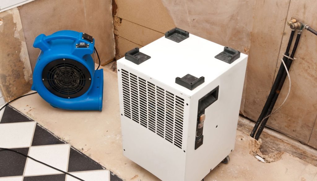 A dehumidifier and fan are set-up in a room to remove moisture during water damage cleanup in a home in Logan, UT.